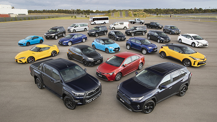 A range of Toyota vehicles, parked and presented for display at Toyota’s Centre of Excellence in Altona, Melbourne in a very large open concrete outdoor area surrounded by a field of lawns and trees.