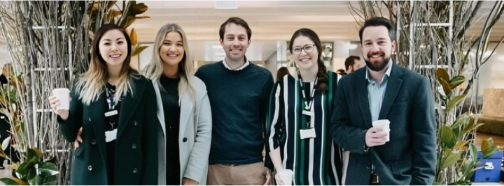 Three women and two men happily huddled together in a line, smiling, during a Toyota National Tree Day event.