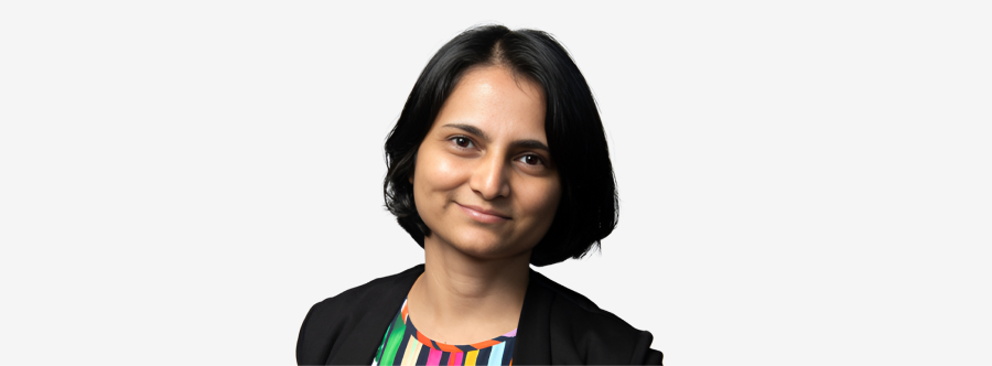 A woman with shoulder-length black hair. She has a slight smile in front of a bright white backdrop.