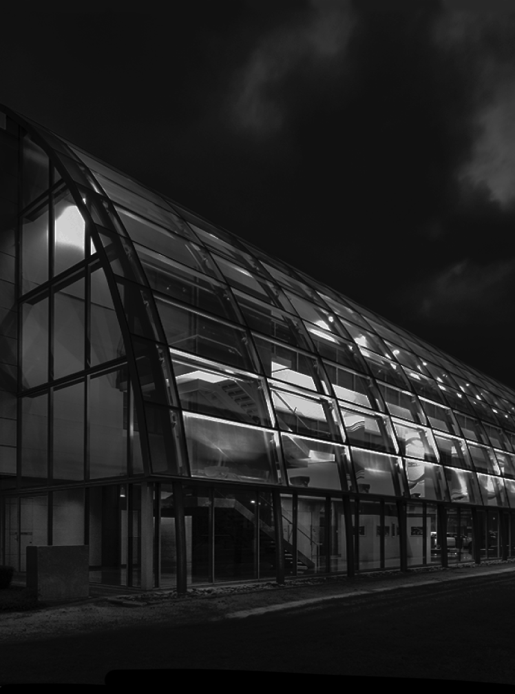 The Toyota Port Melbourne head office from the outside, as a dark black and white shot, lit up from the inside by its internal lighting shining through its curved glass architecture.