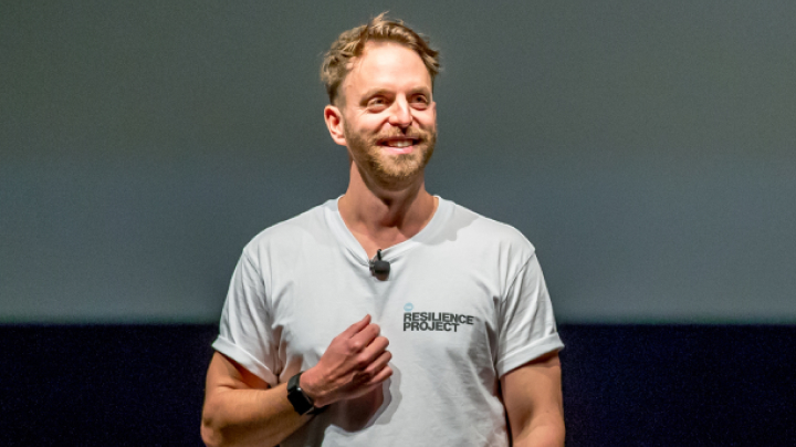 Hugh van Guylenburg giving a presentation on stage at a conference.