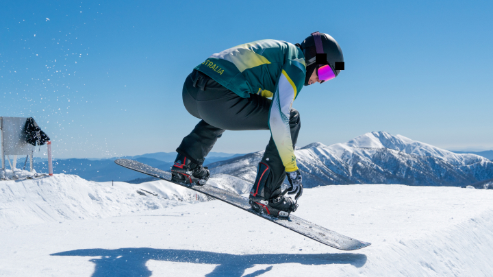 Australian Olympic snowboarder Belle Brockhoff, in a mid-air jump while snowboarding down a mountain.