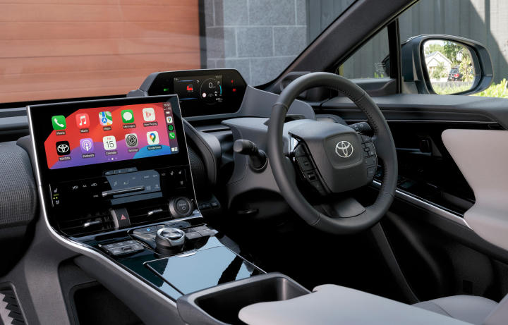 Modern interior of a Toyota, featuring a glossy digital centre console touchscreen, steering wheel and fully digital heads up display.