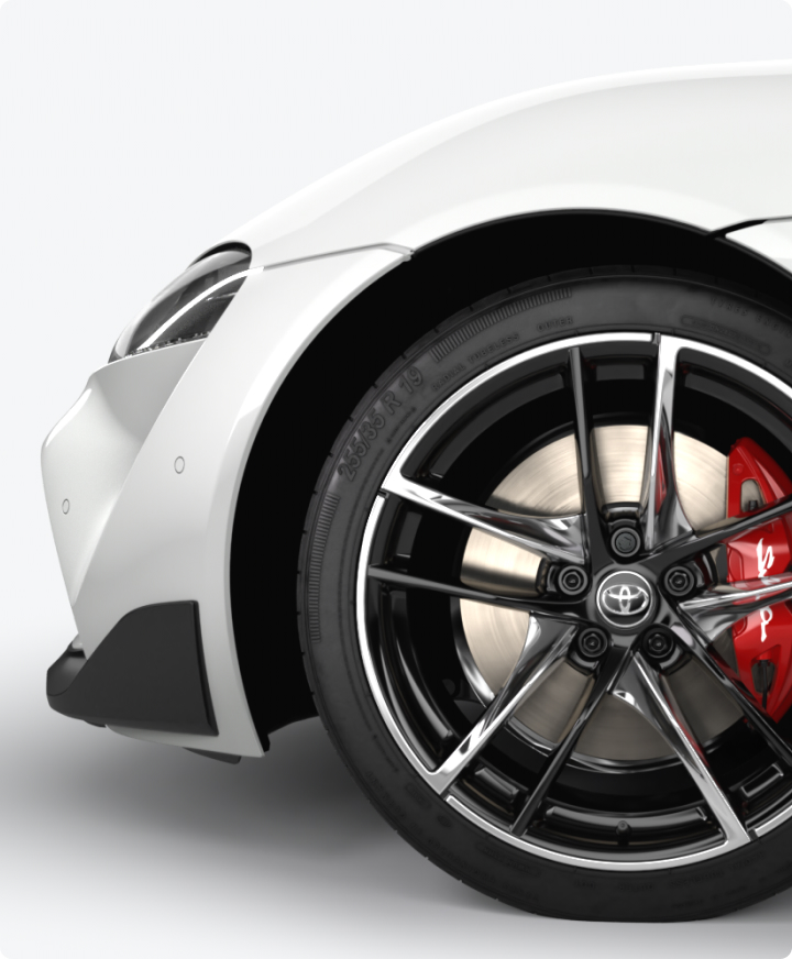 Front wheel of a white GR Supra, with silver alloys and red brake caliper.