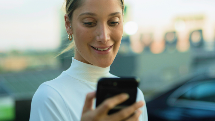 A woman looking down at her smart phone with a satisfied look on her face.