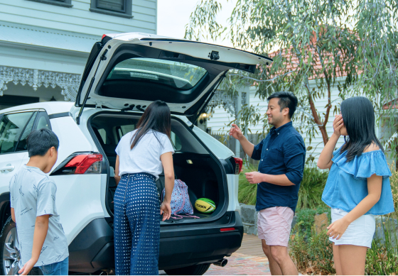 A family unloading recreational sports equipment from their car boot.