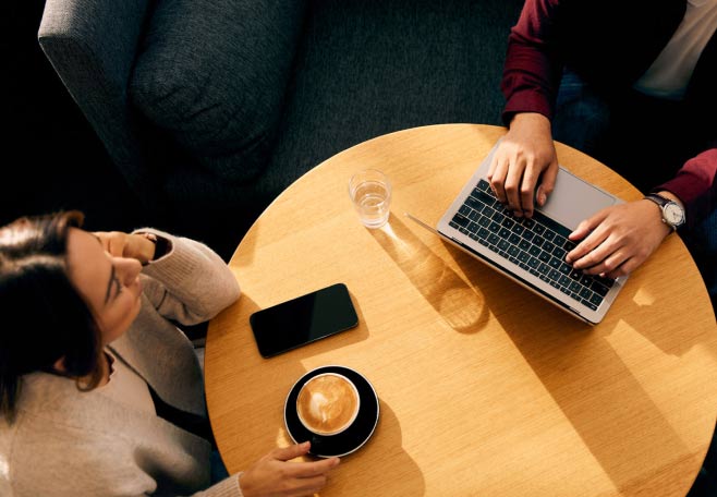 Two people sitting at a coffee table with their laptops open
