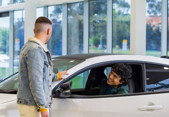 Two friends looking at a Toyota car in a Dealer showroom